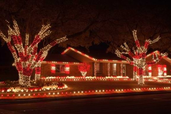 Home decorated with vibrant red and white lights for the holiday season at night.