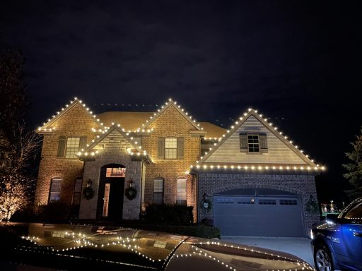 A house decorated with Christmas lights, featuring wreaths on the windows.