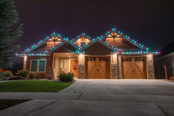 A house decorated with colorful Christmas lights along the roof edges at night.