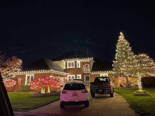A festive house decorated with bright holiday lights and a large Christmas tree.