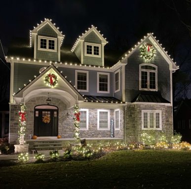 Charming house decorated with Christmas lights and wreaths at night.